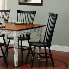 a dining room table with four chairs and a framed photo on the wall above it