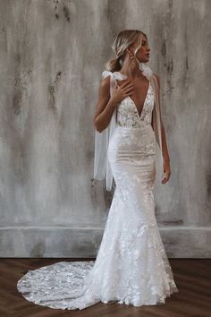 a woman in a white wedding dress standing on a wooden floor