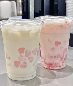 two drinks sitting on top of a table next to each other with pink and white toppings