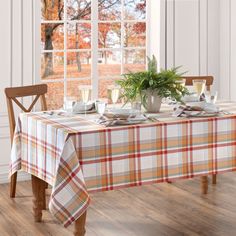 the table is set with dishes and cups on it, next to a potted plant