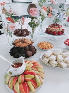 an assortment of desserts and pastries on a table with flowers in the background