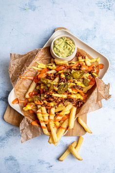 a platter filled with fries and vegetables next to a small bowl of dipping sauce