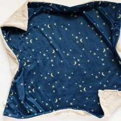 a blue blanket with stars and moon designs on it, sitting on a white surface