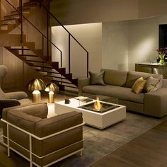 a living room filled with furniture and a fire place next to a stair case on the wall