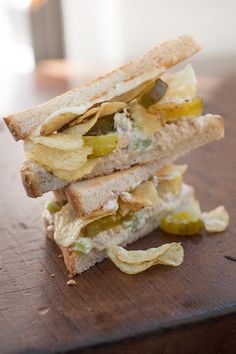 a sandwich is stacked on top of each other with pickles and chips in it