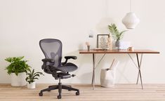 an office chair sitting in front of a desk with potted plants next to it