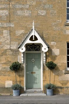 an old building with a green door and two planters on the sidewalk in front of it