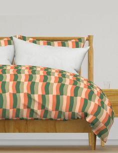 an orange and green comforter on a bed with two pillows in front of it