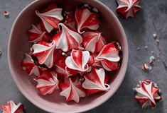 a bowl filled with red and white candies on top of a gray countertop