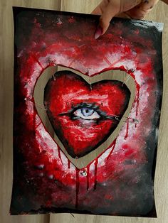 someone holding up a piece of art with an eye in the center and a heart painted on it