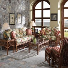 a living room filled with lots of furniture next to a stone wall covered in windows