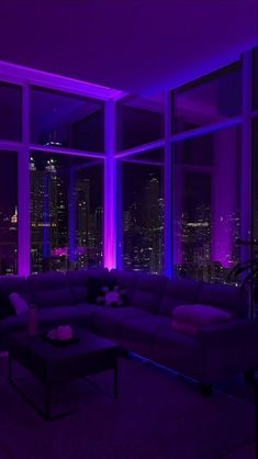 the living room is lit up with purple lighting and large windows that look out onto the city