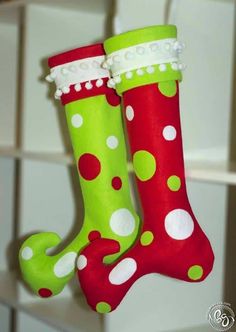 two green and red christmas stockings hanging from a hook with white dots on the bottom