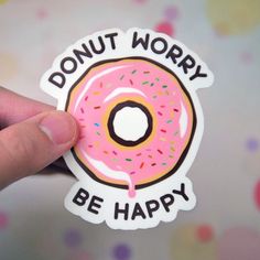 a hand holding a donut sticker that says, donut worry be happy