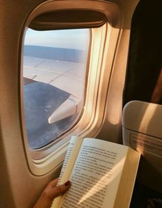 someone is reading a book on an airplane