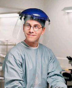 a man with glasses and a helmet on his head is sitting in an operating room