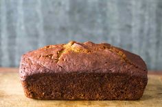 a loaf of brown bread sitting on top of a wooden table next to a knife