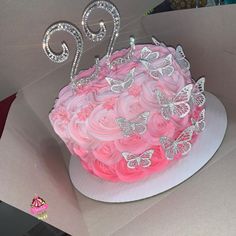 a birthday cake with pink frosting and butterflies on top, sitting in a box