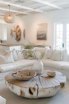 a living room filled with white furniture and lots of pillows on top of the couches