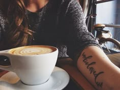 a woman sitting at a table with a cup of coffee in front of her arm