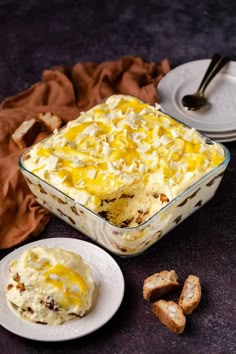 a casserole dish filled with food next to some crackers on a table