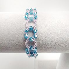 two bracelets with blue and pink beads on top of a white cloth covered arm