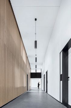 a person walking down a long hallway between two buildings with closed doors on both sides