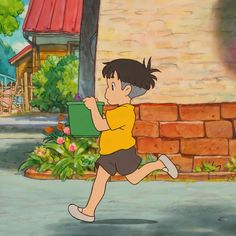 a young boy running down the street in front of a brick building