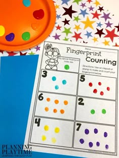 a fingerprint counting game next to a paper plate and some colored stars on the table