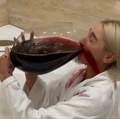 a woman drinking from a wine glass in the bathtub