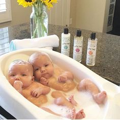 three baby dolls in a bathtub with soap on the side and sunflowers behind them