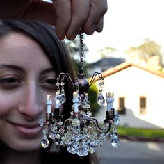 a woman is holding up a chandelier in front of her face and smiling