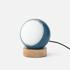 a blue and white lamp sitting on top of a wooden table next to a black cord