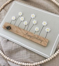 a birthday card with daisies on it and a wooden name tag in the middle