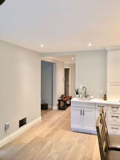 an empty kitchen and dining room with white cabinets, wood floors and hard wood flooring