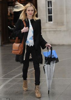 a woman walking down the street with an umbrella and leopard print purse on her shoulder