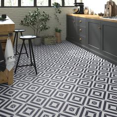 a kitchen with black and white tile flooring next to a counter top, potted plant on stools