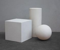 two white vases sitting next to each other on top of a cement floor covered ground