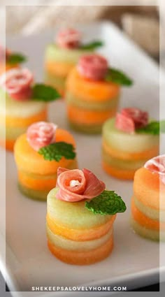 small desserts on a white plate with green leaves and pink flowers in the middle