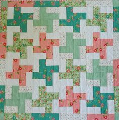 a close up of a quilt made with squares and flowers in pastel green, pink and white colors