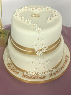 a wedding cake with white flowers and gold trim