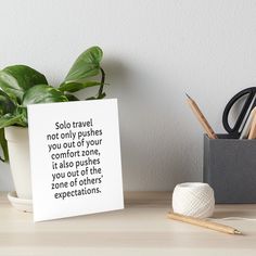 a white card with a quote on it sitting next to a potted plant art board print