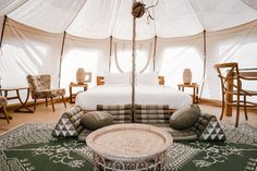 a bed sitting inside of a tent on top of a green rug