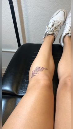 a woman's legs with a tattoo on her left leg sitting in a chair