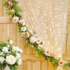 two vases filled with flowers sitting on top of a table next to a curtain