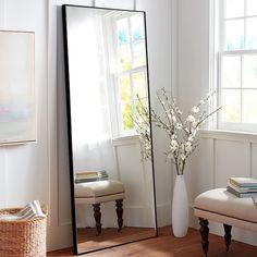 a mirror sitting on top of a wooden floor next to a vase filled with flowers