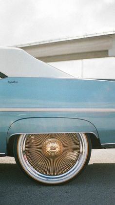 an old blue car with gold rims parked in front of a building