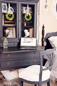 a desk with a chair and a computer on it in front of a dresser that is decorated with wreaths