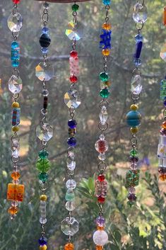 a wind catcher made out of beads hanging from the side of a window sill