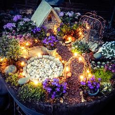 a small garden with flowers and lights in the center is displayed on top of a barrel